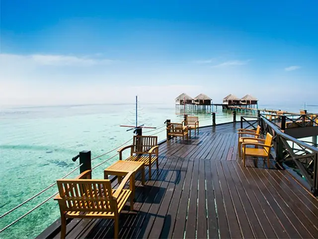 A timber jetty running out to overwater villas on a lagoon