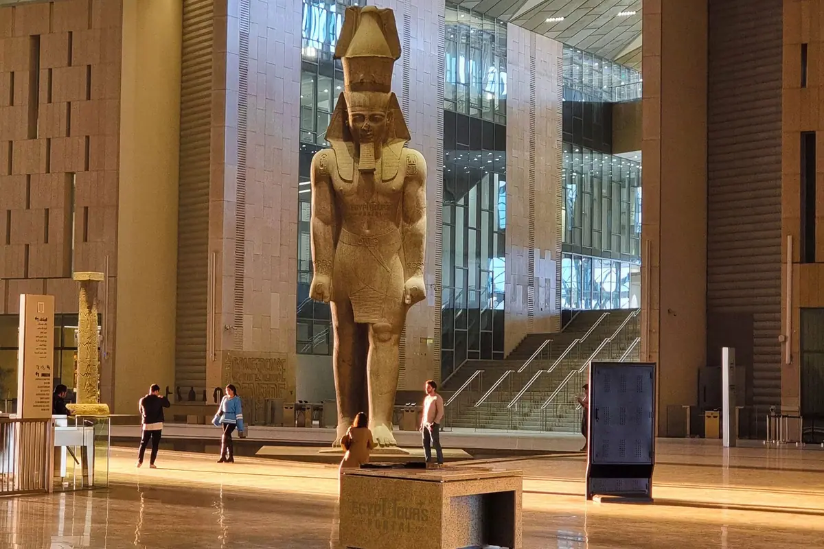 A colossal pharaonic statue standing in a museum hall in Egypt
