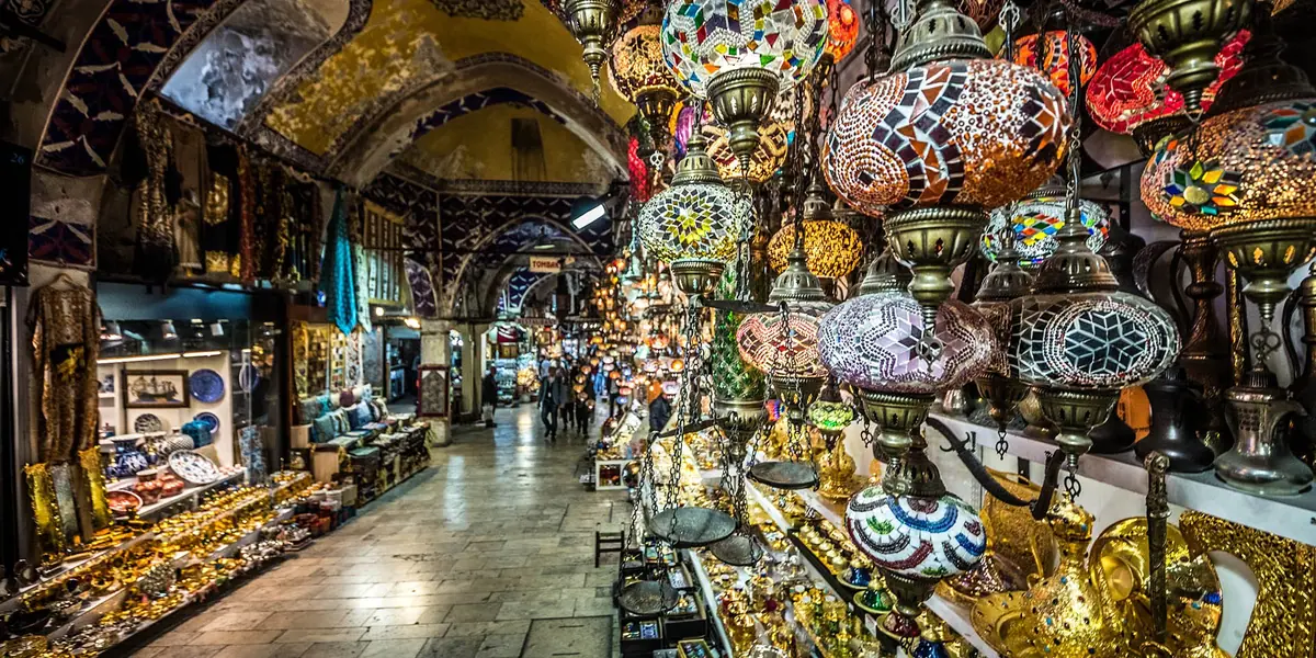 A shopper browsing a spice and Turkish delight stall inside an Istanbul bazaar