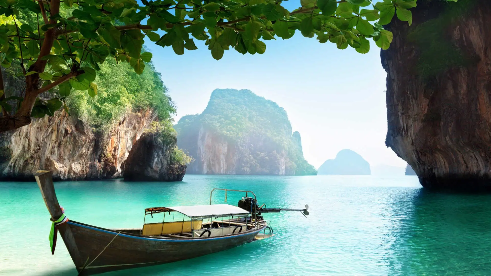 A longtail boat below limestone cliffs in the Andaman Sea