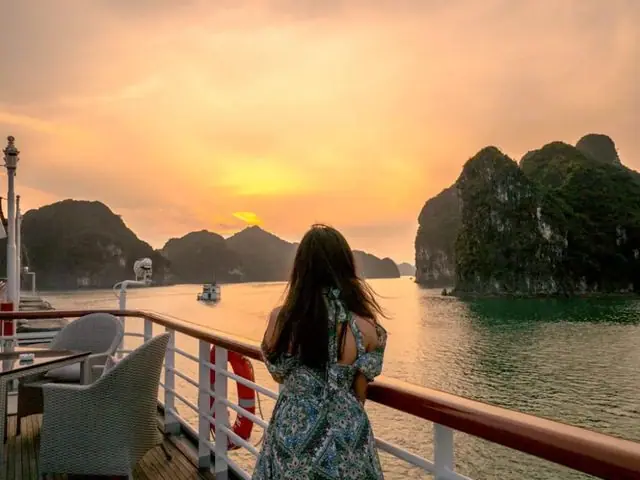 A passenger at the deck rail watching the sunset from a cruise ship
