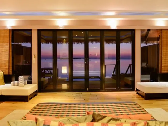 A suite living area opening onto a sea view at dusk